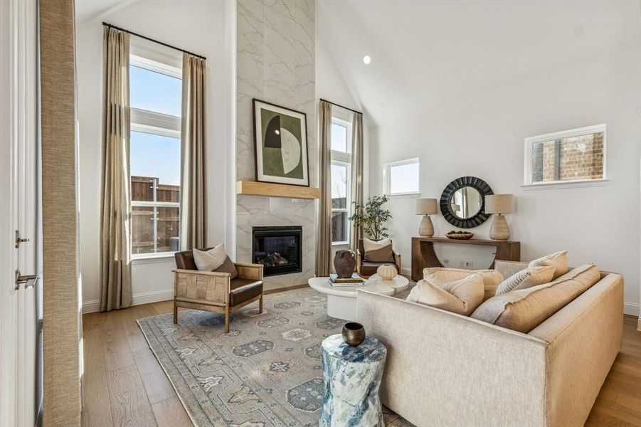 Living room with a premium fireplace, light wood finished floors, vaulted ceiling, and recessed lighting
