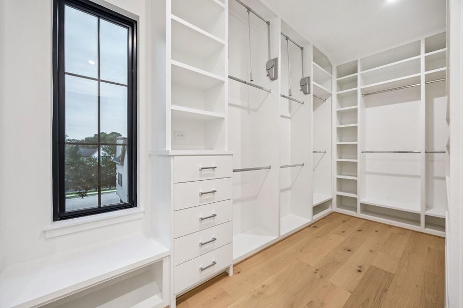Partial view of the Primary Closet with built-in dresser drawers, pulldowns, chrome rods and more.