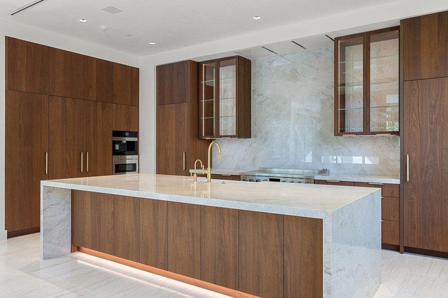 Kitchen featuring light stone countertops, modern cabinets, glass insert cabinets, and a large island