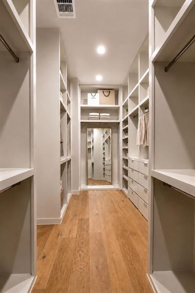 Primary closet fit for a king or queen with soft closing drawers, angled shoe storage, and hanging rods for all lengths.