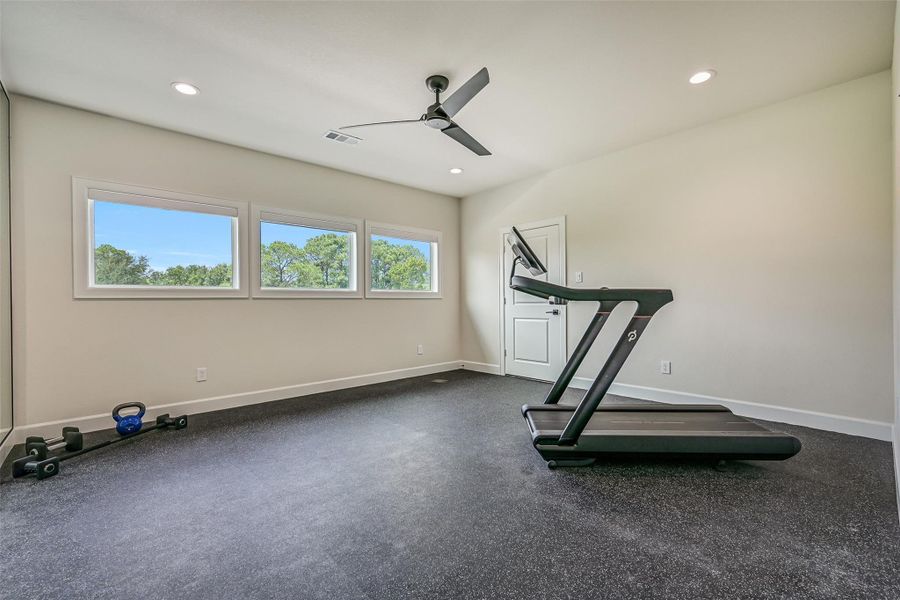 Currently outfitted as a home gym, this large upstairs flex room serves as the home’s 6th bedroom and features three oversized windows, a ceiling fan, recessed lighting, durable rubber flooring and an impressively sized closet.
