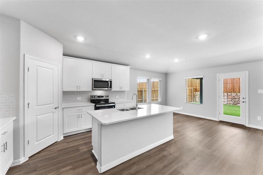 Kitchen featuring stainless steel appliances, dark wood-style flooring, tasteful backsplash, light countertops, and recessed lighting Kitchen featuring stainless steel appliances, dark wood-style flooring, tasteful backsplash, light countertops, and recessed lighting