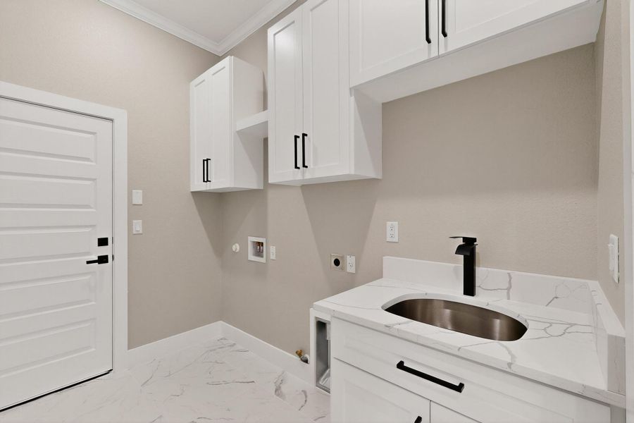 Washroom with gas dryer hookup, tile flooring, hookup for a washing machine, crown molding, and cabinet space Washroom with gas dryer hookup, tile flooring, hookup for a washing machine, crown molding, and cabinet space
