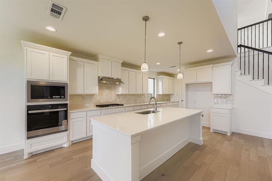 Kitchen featuring appliances with stainless steel finishes, decorative backsplash, white cabinets, pendant lighting, and recessed lighting Kitchen featuring appliances with stainless steel finishes, decorative backsplash, white cabinets, pendant lighting, and recessed lighting