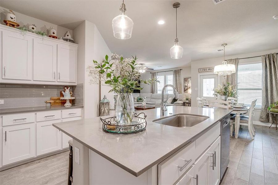 Kitchen with light wood finished floors, tasteful backsplash, light countertops, stainless steel dishwasher, and a sink