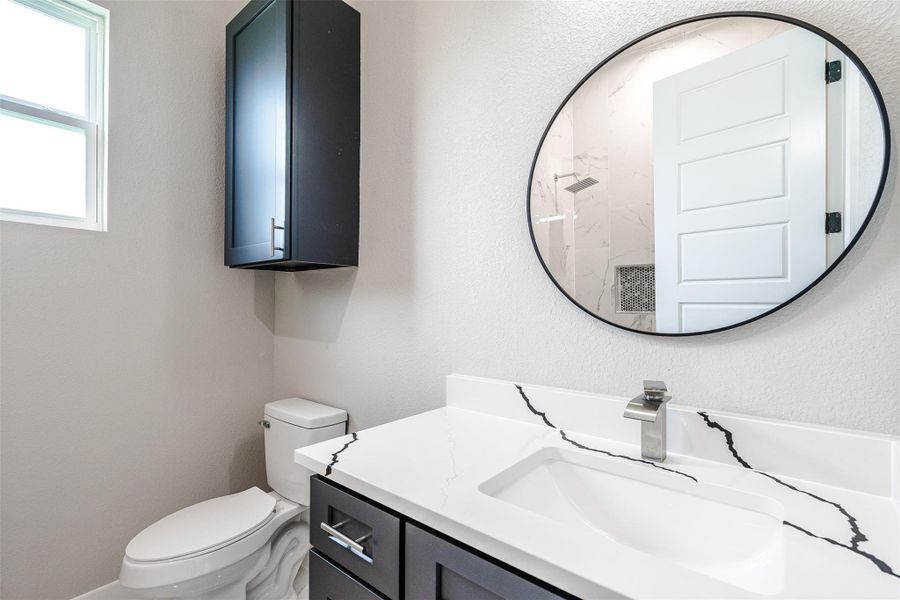 A well-lit primary bathroom with modern fixtures and a large vanity mirror. A well-lit primary bathroom with modern fixtures and a large vanity mirror.