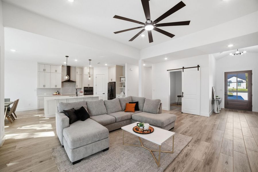 Living area with a barn door, ceiling fan, recessed lighting, light wood finished floors, and a chandelier Living area with a barn door, ceiling fan, recessed lighting, light wood finished floors, and a chandelier