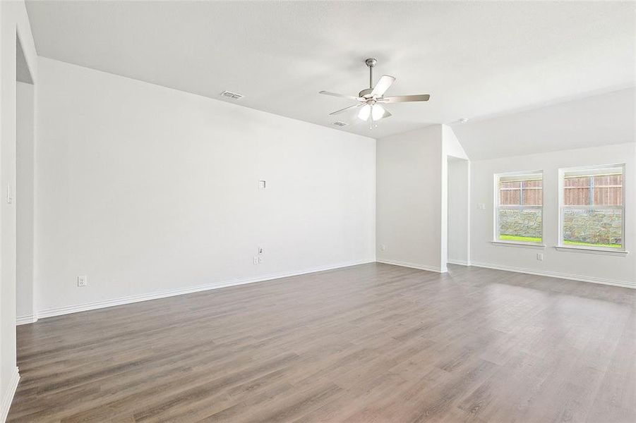 Unfurnished room featuring wood-type flooring, ceiling fan, and lofted ceiling