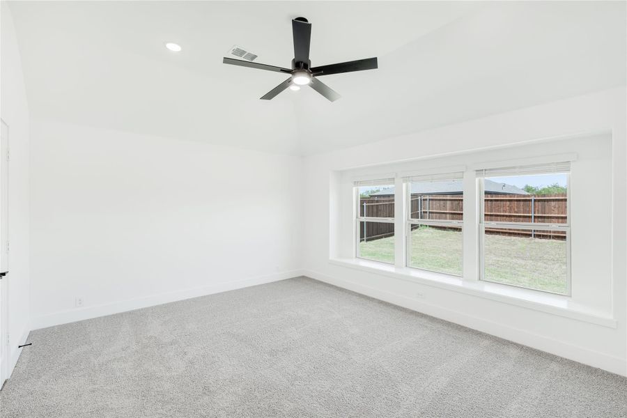 Empty bedroom with gray carpet, black ceiling fan, and large window overlooking backyard Empty bedroom with gray carpet, black ceiling fan, and large window overlooking backyard