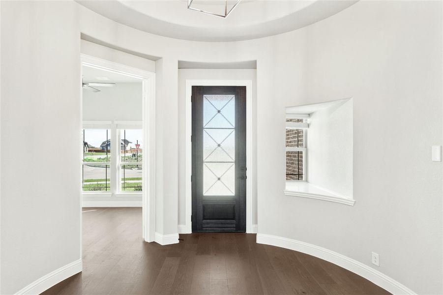 Curved foyer with dark wood floors, glass-panel front door, and tray ceiling Curved foyer with dark wood floors, glass-panel front door, and tray ceiling