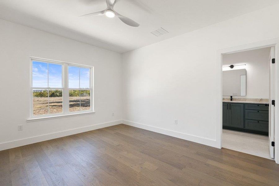 Unfurnished bedroom with light wood-style floors, a ceiling fan, and ensuite bathroom