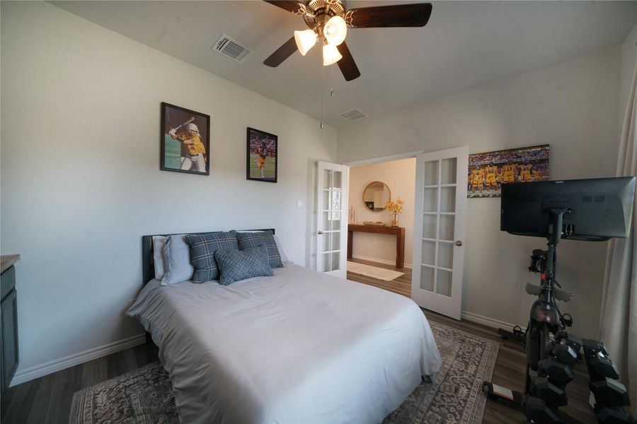 Bedroom featuring french doors, dark wood-style flooring, and a ceiling fan