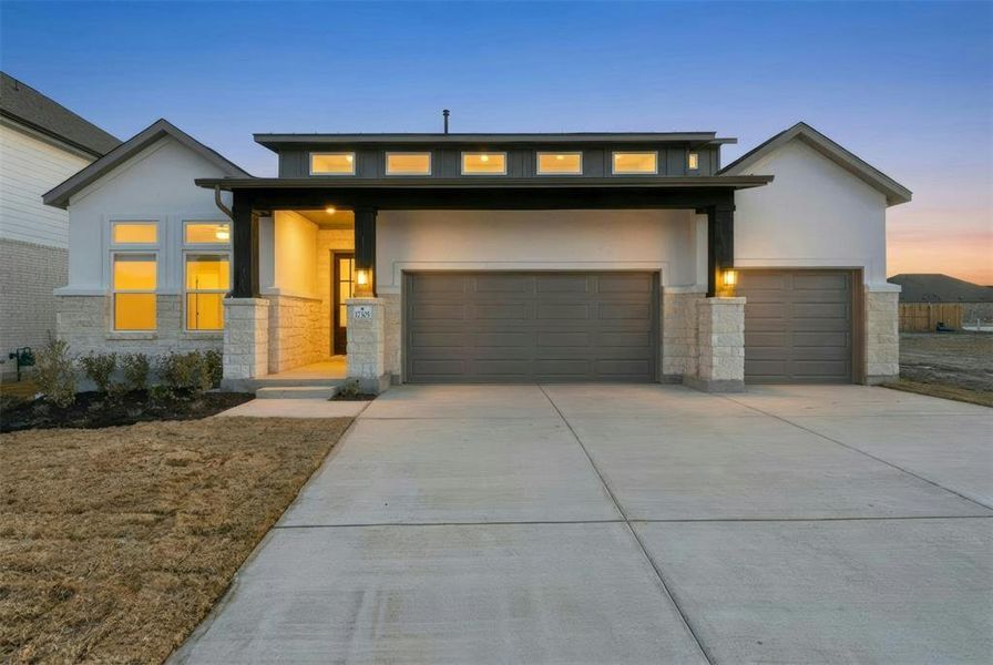 Modern exterior featuring a prominent two-car garage, stone accents, and a covered entry