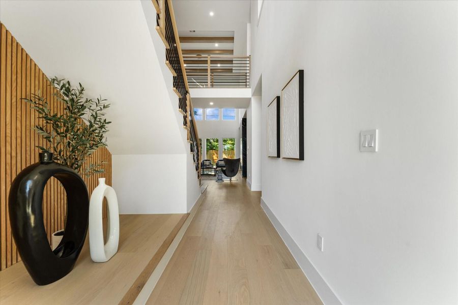 This modern entrance hallway features sleek wood paneling and a staircase with metal railings. It leads to a bright living area with large windows, creating an open and airy atmosphere. This modern entrance hallway features sleek wood paneling and a staircase with metal railings. It leads to a bright living area with large windows, creating an open and airy atmosphere.
