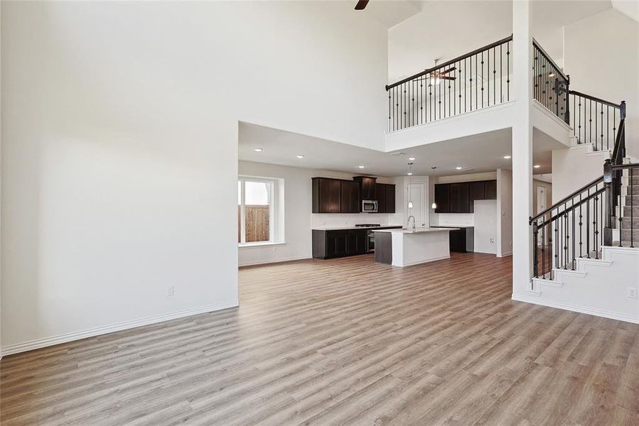 Unfurnished living room with light hardwood / wood-style flooring, sink, and a high ceiling