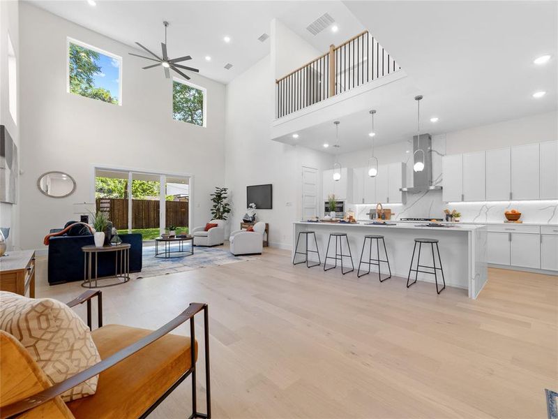 Living room with recessed lighting, light wood-style flooring, ceiling fan, and a towering ceiling
