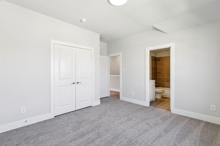 Unfurnished bedroom with light carpet, ensuite bath, and a closet Unfurnished bedroom with light carpet, ensuite bath, and a closet