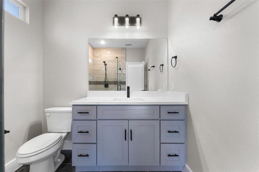 Bathroom featuring vanity, toilet, a shower with shower door, and tile patterned flooring