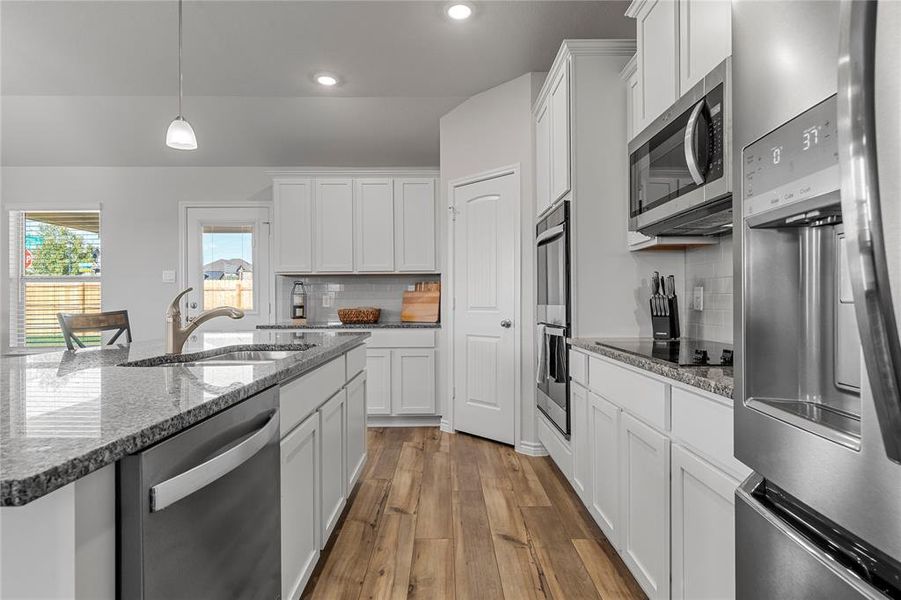Kitchen featuring hanging light fixtures, white cabinetry, dark stone counters, and recessed lighting