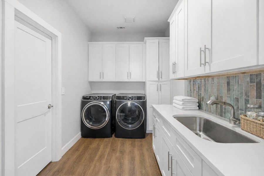 Laundry room featuring dark wood-type flooring, washing machine and dryer, and cabinet space