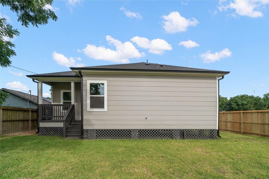 This photo showcases the side view of a single-story home with light gray siding and a dark roof. It features a small covered porch with steps leading to a fenced backyard, perfect for privacy and outdoor activities. This photo showcases the side view of a single-story home with light gray siding and a dark roof. It features a small covered porch with steps leading to a fenced backyard, perfect for privacy and outdoor activities.