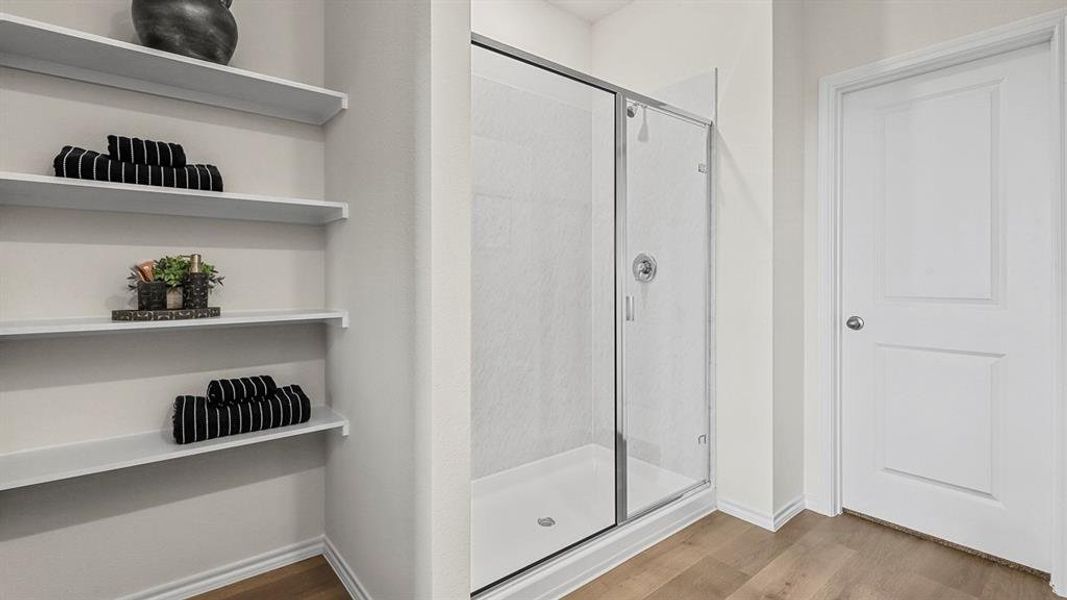 Full bath featuring light wood-style flooring, a shower stall, and a closet