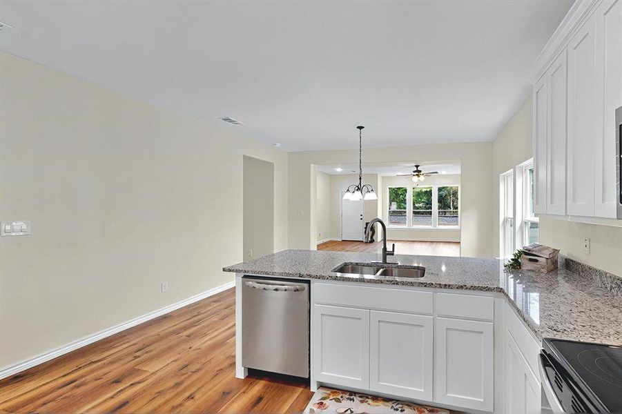 Kitchen with white cabinets, a sink, dishwasher, light wood-style flooring, and a peninsula Kitchen with white cabinets, a sink, dishwasher, light wood-style flooring, and a peninsula