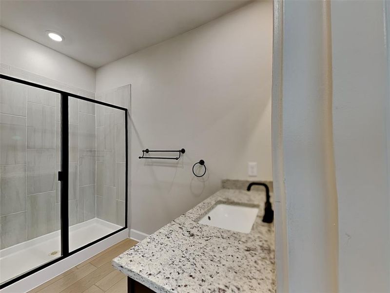 Bathroom featuring wood-type flooring, an enclosed shower, and vanity