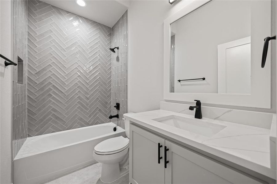 Bathroom featuring a herringbone-patterned tile shower surround, a built-in shower niche, a white soaking tub, and a vanity with a white countertop and integrated sink