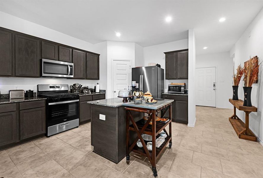 Open Kitchen featuring an island, walk in pantry, and a gas stove. The Kitchen is open to the dining area and the Living Room