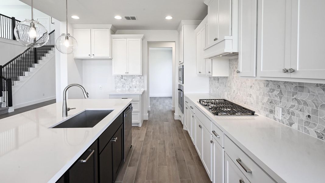 Kitchen featuring recessed lighting, wood finished floors, white cabinets, light countertops, and dark cabinets