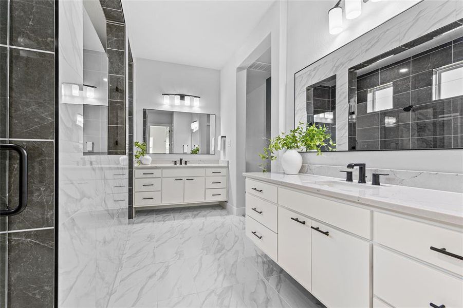 Bathroom with two vanities, light marble finish floors, and a stall shower