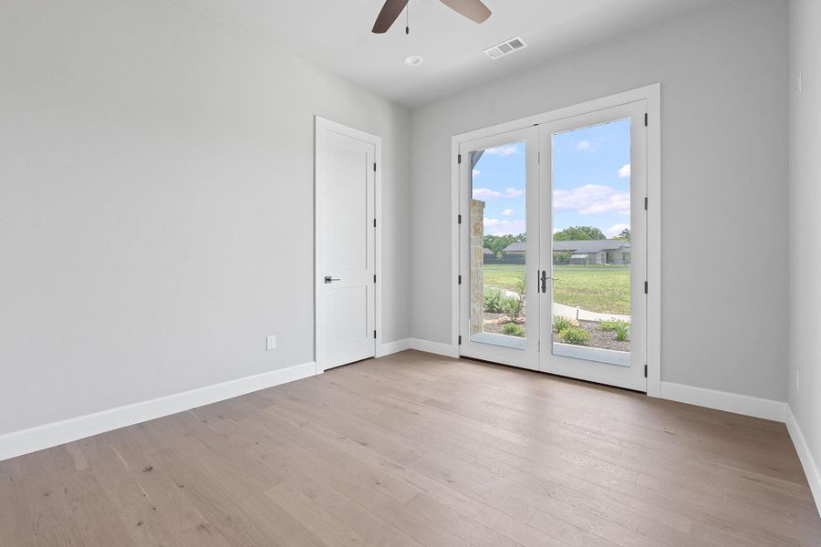 Spare room with a ceiling fan, light wood-style flooring, and french doors