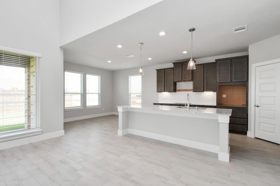 Culinary haven, featuring granite countertops, a tile backsplash, stainless steel appliances (to be installed), and 42” upper cabinets. Sample photo of completed home with similar floor plan. Actual colors and selections may vary.