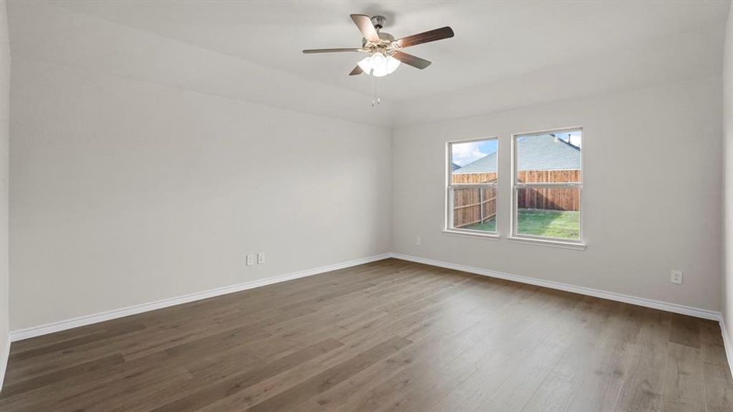 Spacious interior featuring wood-finish flooring, light grey walls, and a ceiling fan with integrated lighting