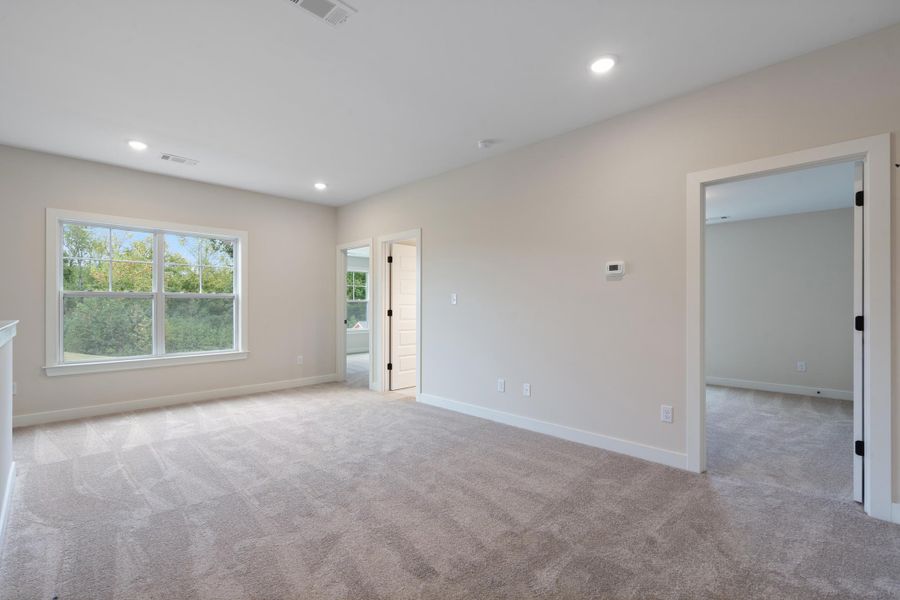 Spacious carpeted room with recessed lighting, a large window, and light-toned wall paint Spacious carpeted room with recessed lighting, a large window, and light-toned wall paint