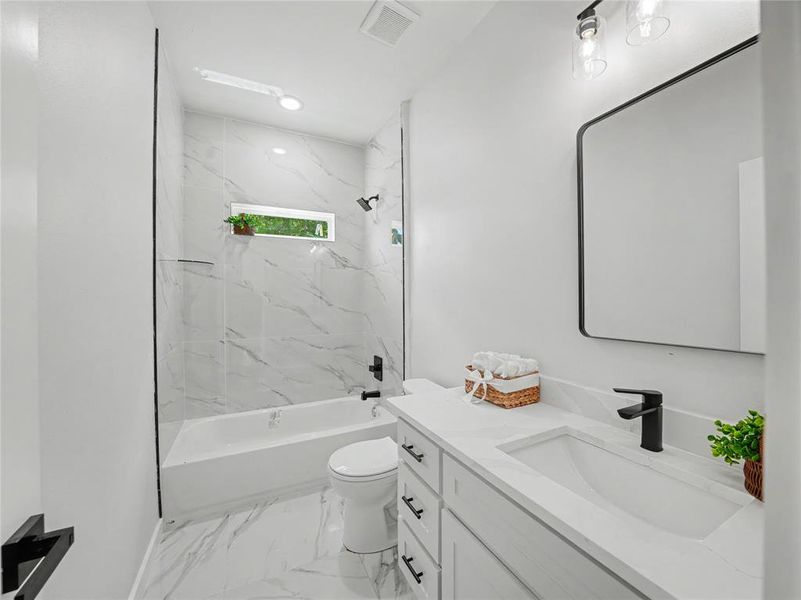 Full bath featuring vanity, a combined bath / shower with marble appearance, and light marble finish flooring