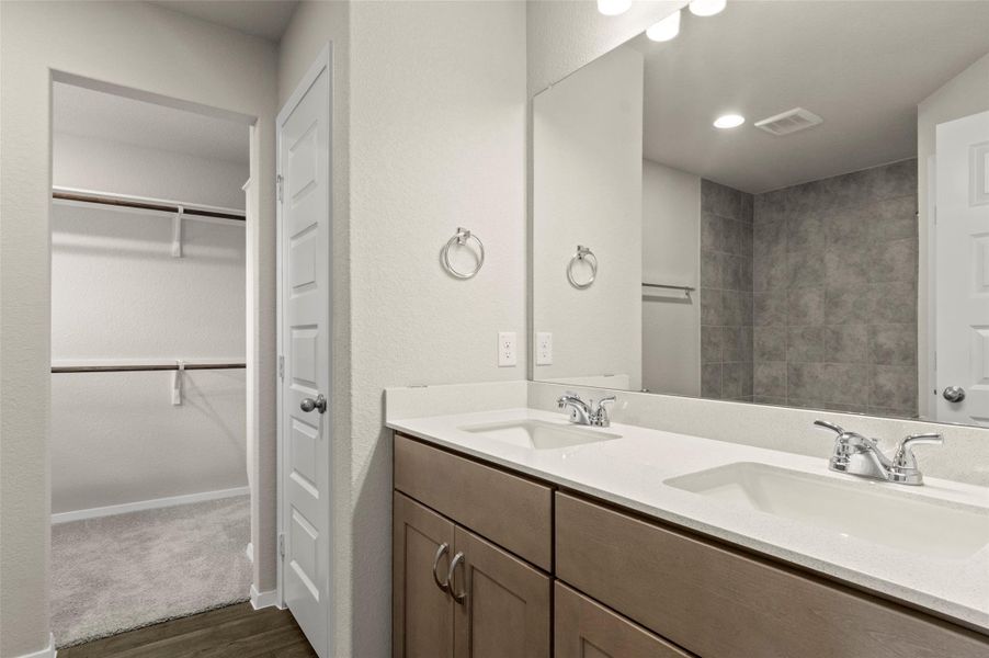 Bathroom featuring wood finished floors, double vanity, and a walk in closet