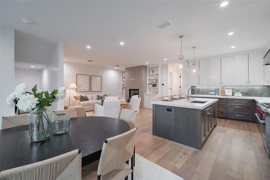 Kitchen featuring decorative light fixtures, sink, white cabinets, dark brown cabinetry, and light hardwood / wood-style flooring