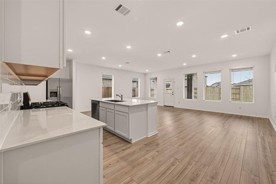 Spacious open-concept living area with upgraded flooring and a seamless flow between the kitchen, dining, and family room—perfect for everyday living and entertaining.