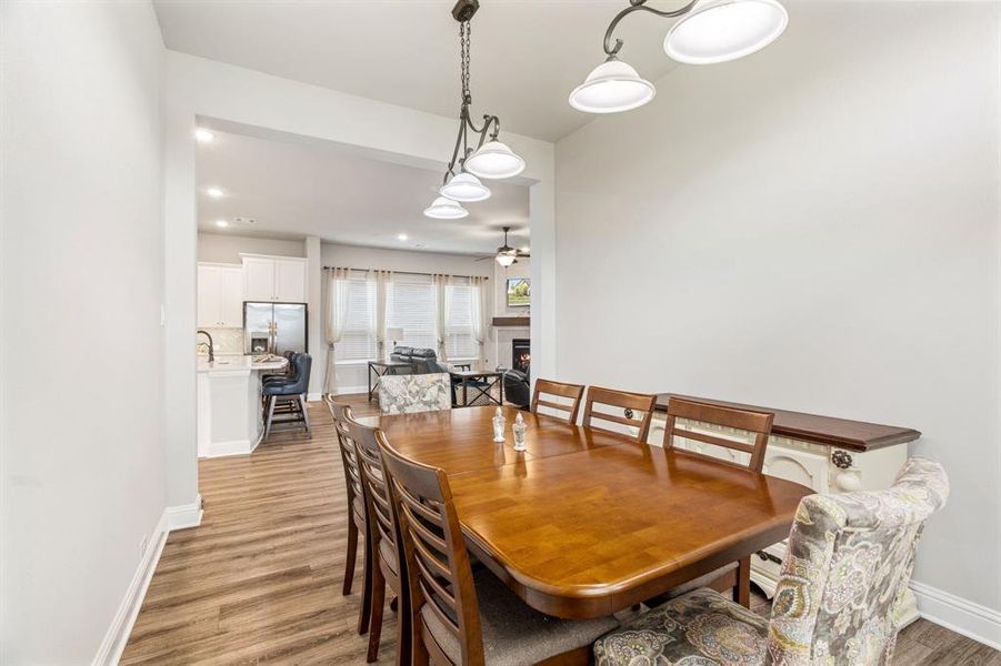 Dining space featuring wood-finish flooring, a multi-light chandelier, and a wide entryway Dining space featuring wood-finish flooring, a multi-light chandelier, and a wide entryway