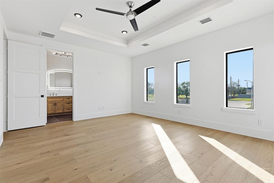 Multiple vertical windows provide ample natural light to the primary suite, which connects directly to the en-suite bathroom.