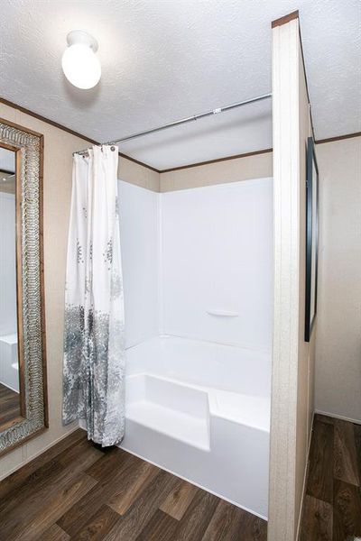 Bathroom with shower / bathtub combination with curtain, a textured ceiling, and hardwood / wood-style floors