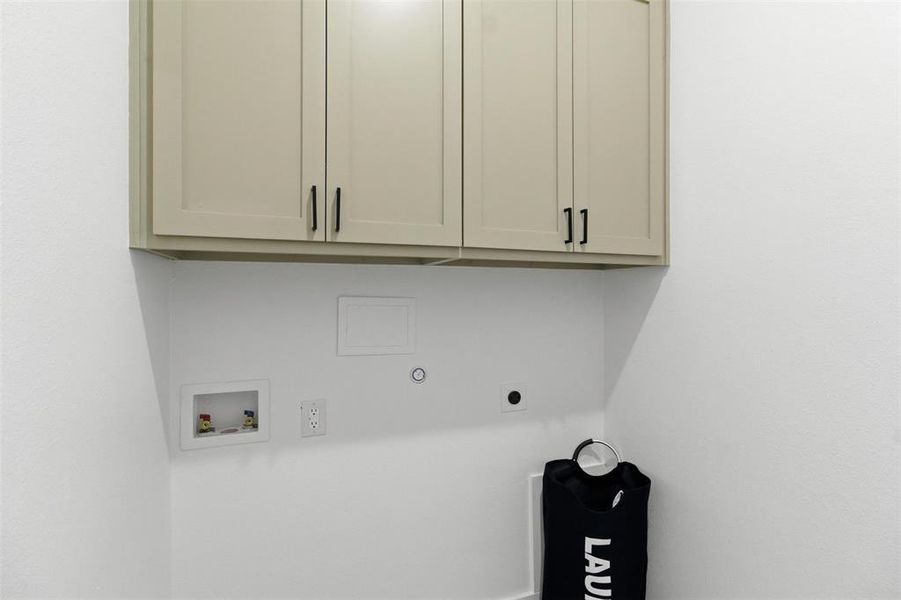 Functional utility area featuring two upper cabinets with matte black hardware, white walls, and dedicated hookups for appliances