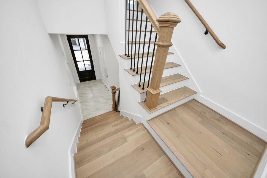 As you step into your bright, modern entryway with a staircase, you are greeted with stone tiled flooring, wooden custom handrails with white risers, leading to the upper second level. There's a glimpse into your well-lit secondary room with private en-suite bathroom. As you step into your bright, modern entryway with a staircase, you are greeted with stone tiled flooring, wooden custom handrails with white risers, leading to the upper second level. There's a glimpse into your well-lit secondary room with private en-suite bathroom.