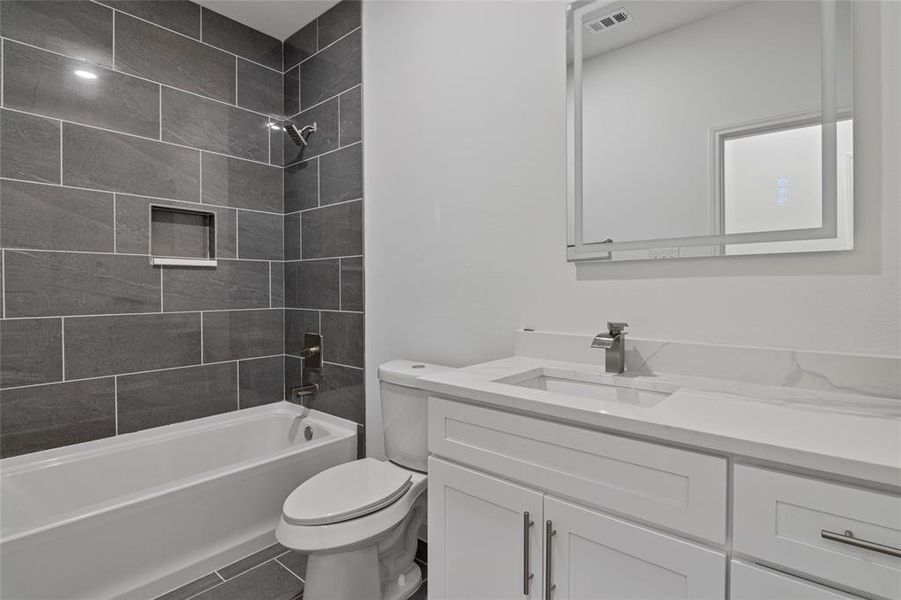 Full bathroom with tile patterned flooring, tiled shower / bath, vanity, and toilet