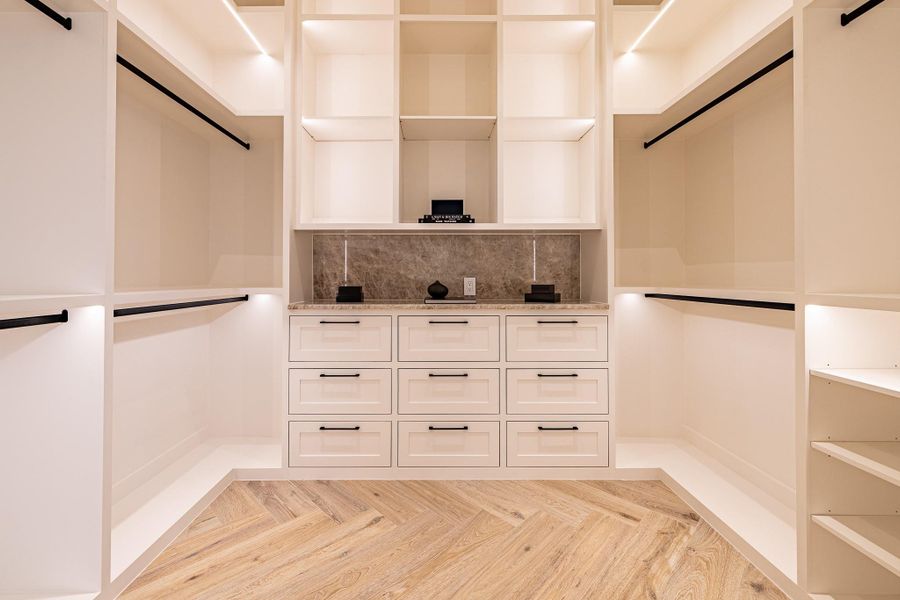 One of two custom primary closets (“his side”) featuring extensive built-ins and organized wardrobe storage. One of two custom primary closets (“his side”) featuring extensive built-ins and organized wardrobe storage.