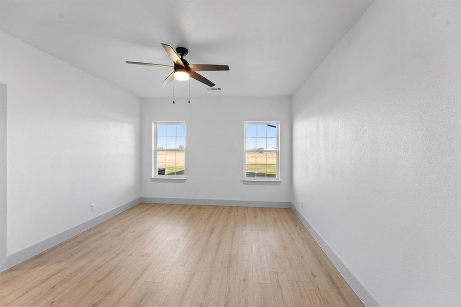 Empty room with light wood-style floors and ceiling fan