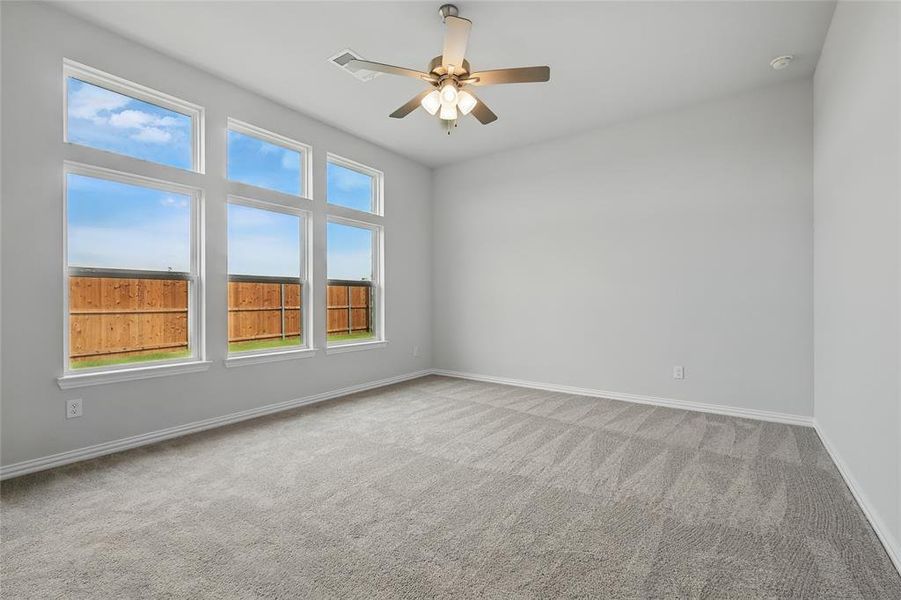Carpeted empty room with baseboards and a ceiling fan Carpeted empty room with baseboards and a ceiling fan