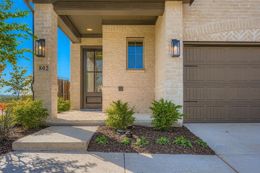 Doorway to property featuring covered porch, a garage, and stone siding